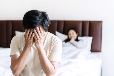 Husband feels stressed and pressured from the problem of erectile dysfunction while the disgruntled wife lay in bed after having sexの写真素材