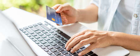 Young woman holding a credit card and using computer for making online payment shoppingの写真素材