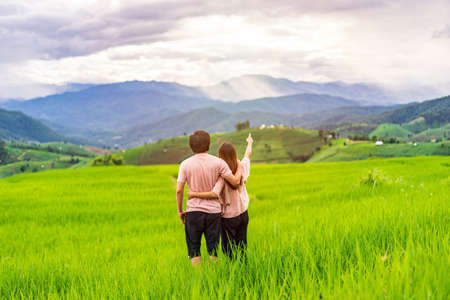 Young couple traveler on vacation enjoying and looking at beautiful green rice terraces field in Pa Pong Pieng, Chiangmai Thailandの写真素材