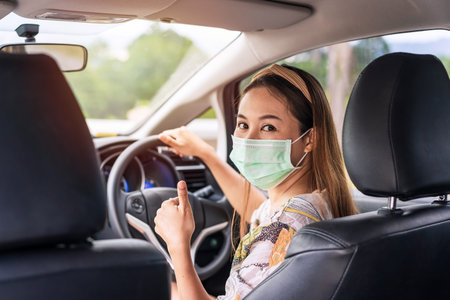 The female driver wearing surgical mask felt confident and gesturing thumbs up while traveling