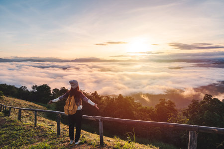 Young woman travelers looking at the sunrise and the sea of mist on the mountain in the morning, Travel lifestyle conceptの写真素材