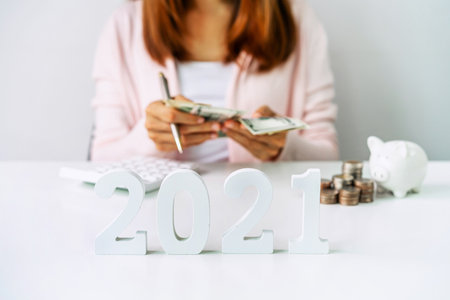 Young woman calculating expenses with stack of coins and piggy bank, 2021 Saving money for future investment conceptの写真素材