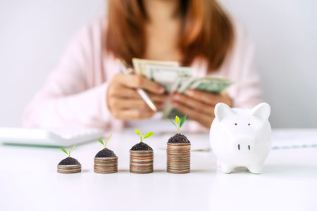 Young woman calculating expenses with stack of coins and piggy bank, Saving money for future...