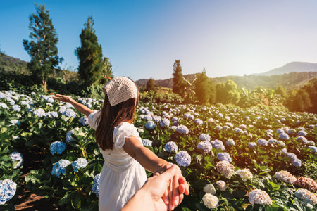 Young couple traveler relaxing and enjoying with blooming hydrangeas flower field in Thailand, Travel lifestyle conceptの写真素材