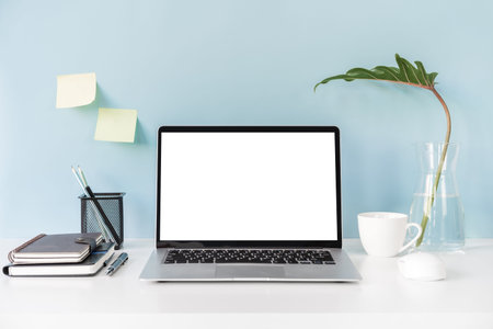 Modern and stylish workspace mock up with blank laptop and desk office supplies with color...