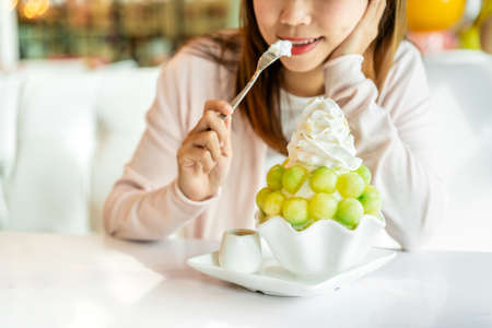 Young woman enjoy eating melon bingsu in restaurantの写真素材