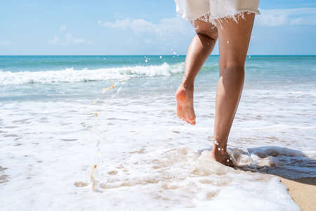 Young woman running on the tropical beach in sunny day, Summer vacation conceptの写真素材