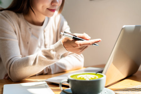 Young woman with a cup of coffee working in a video call at the restaurant