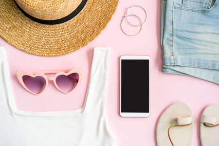 Fashion summer women's clothes set with accessories on pink background with empty screen smart phone, Flat lay, Top viewの写真素材