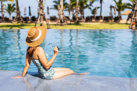 Young woman traveler relaxing and enjoying by a tropical resort pool while traveling for summer vacation, Travel conceptの写真素材