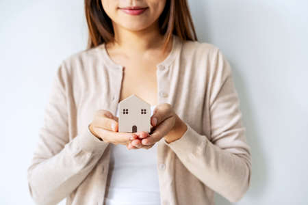 Hand of young woman holding wooden house model, Real estate conceptの写真素材
