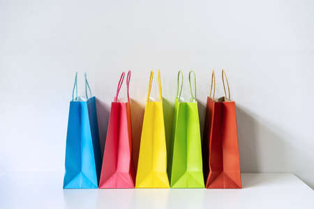 Colorful paper shopping bags on white table and background with copy spaceの写真素材