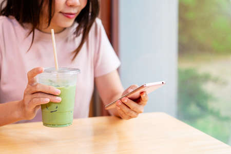 Young woman with drinks using mobile phone and relaxing in cafe, Modern lifestyleの写真素材