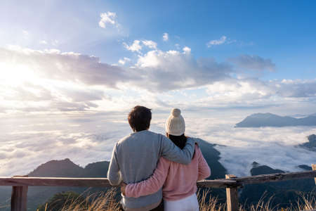 Young couple travelers looking at the sunrise and the sea of mist on the mountain in the morning, Travel lifestyle conceptの写真素材