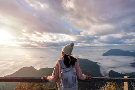 Young woman travelers looking at the sunrise and the sea of mist on the mountain in the morning, Travel lifestyle conceptの写真素材