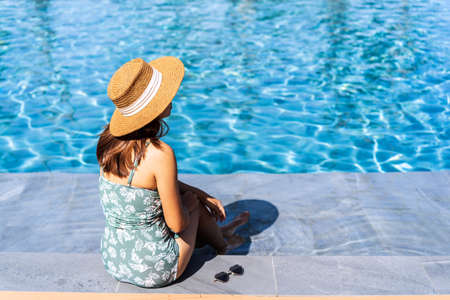 Young woman traveler relaxing and enjoying by a tropical resort pool while traveling for summer vacation, Travel conceptの写真素材