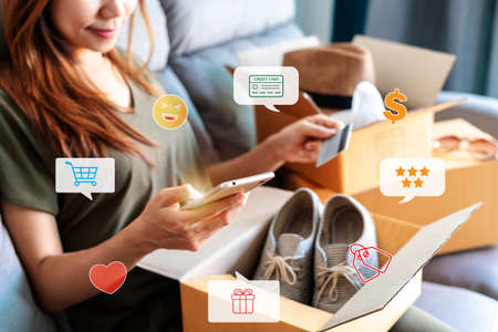 Young woman received online shopping parcel opening boxes and buying fashion items by using credit card, Shop online payment icon and delivery conceptの写真素材