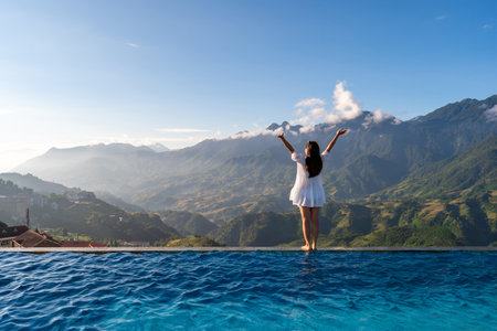 Young woman traveler relaxing at sky pool and looking at the beautiful nature landscape with blue sky and mountains in Sapa, Vietnamの写真素材