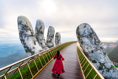 Young woman traveler in red dress enjoying at Golden Bridge in Bana hills, Danang Vietnam, Travel lifestyle conceptの写真素材