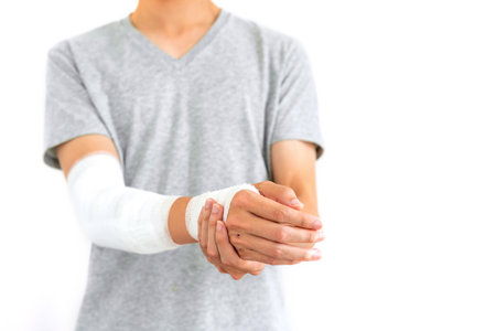 Young man with gauze bandage wrapped around injury hand on white backgroundの写真素材