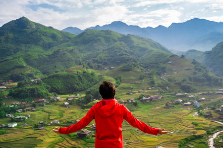 Young man traveler standing and looking at view of green rice terraces in Sapa, Vietnamの写真素材