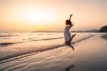 Young woman traveler relaxing and enjoying the beautiful sunset on the tranquil beach, Travel on the summer vacation conceptの写真素材