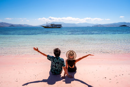 Young couple tourism enjoying the tropical pink sandy beach with clear turquoise water at Komodo islands in Indonesiaの写真素材