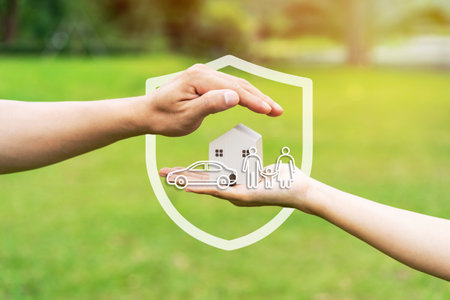 Close-up of hand holding wooden house model with car, family and health insurance icons and conceptの写真素材