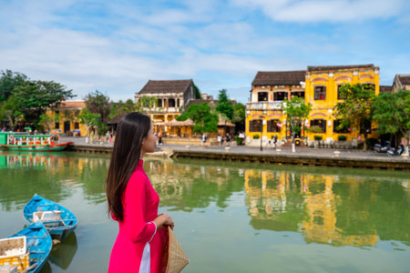 Young female tourist in Vietnamese traditional dress walking at Hoi An Ancient town in Vietnamの写真素材