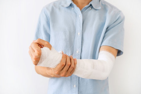 Young man with gauze bandage wrapped around injury hand on white backgroundの写真素材