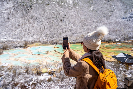 Young happy female traveler enjoying and taking a photo at Huanglong National Park in Sichuan, Chinaの写真素材