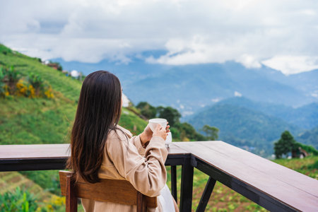 Young woman traveler drinking coffee and enjoying the beautiful nature landscape with mountain viewの写真素材
