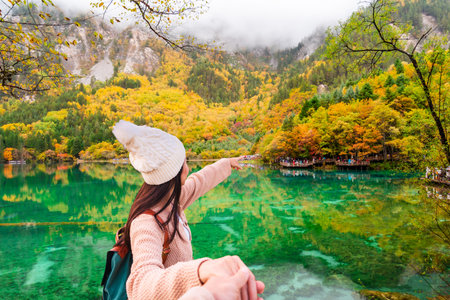 Young couple tourist enjoying the Beautiful autumn scenic view at five flower lake in Jiuzhaigou national parkの写真素材