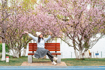 Young female tourist taking selfie with beautiful full bloom cherry blossom on a clear spring dayの写真素材