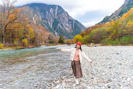 Young happy female tourist relaxing and enjoying with beautiful nature autumn foliage at kamikochi in Japanの写真素材