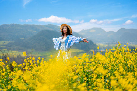 Young happy woman tourist enjoying the canola fields while traveling in Luoping, Chinaの写真素材