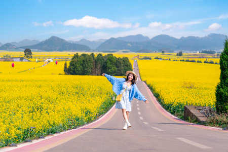 Young happy woman tourist enjoying the canola fields while traveling in Luoping, Chinaの写真素材