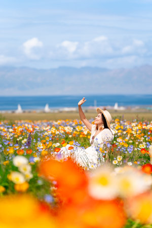 Young woman traveler relaxing and enjoying at beautiful blooming poppy flower fields at sayram lake in Xinjiang, Chinaの写真素材