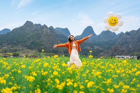 Young happy woman tourist enjoying the canola fields and mountains while traveling in Wanfenglin, Chinaの写真素材