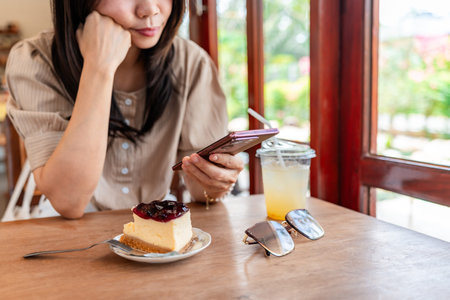 Stress and distraught young Asian woman using smart phone in cafeの写真素材