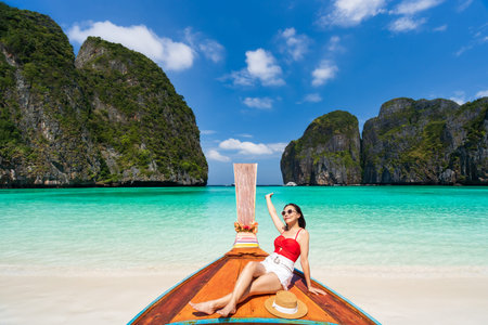 Young woman traveler sitting on a long tail boat relaxing and enjoying at beautiful tropical nature landscape, Summer vacation and Travel conceptの写真素材