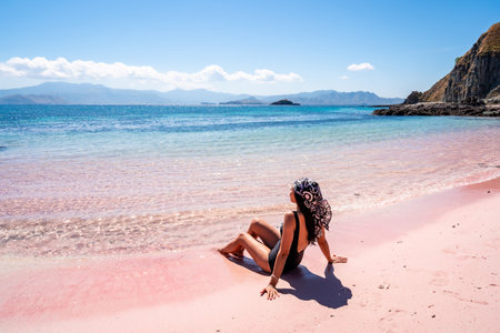 Young female tourism enjoying the tropical pink sandy beach with clear turquoise water at Komodo islands in Indonesiaの写真素材