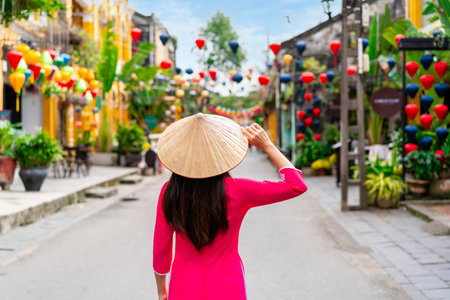 Young female tourist in Vietnamese traditional dress walking at Hoi An Ancient town in Vietnamの写真素材