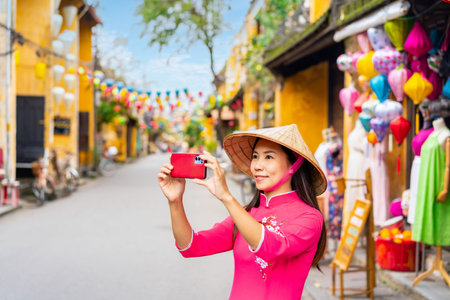 Young female tourist in Vietnamese traditional dress walking at Hoi An Ancient town in Vietnamの写真素材