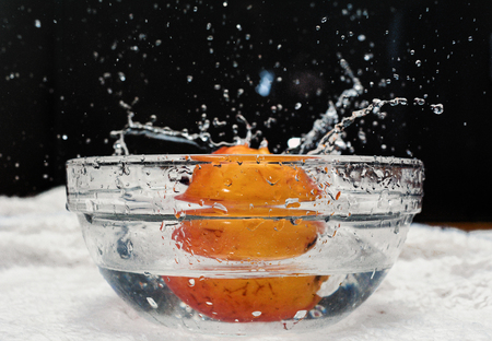 Ripe apple falling into a bowl of waterの写真素材