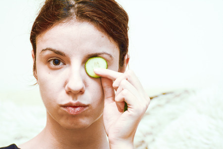 Redhead model using cucumber slices for the dark circles under her tired and puffy eyesの写真素材