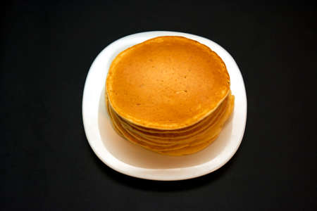 Piled up sweet, delicious pancakes on a white plateの写真素材