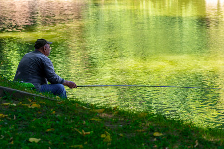 Unrecognizable middle aged man fishing in the park lake in Bucharest, Romania