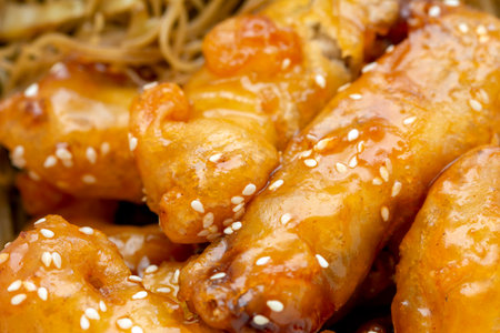 Chicken meat dipped in an orange sauce crust with noodles as garnishの写真素材