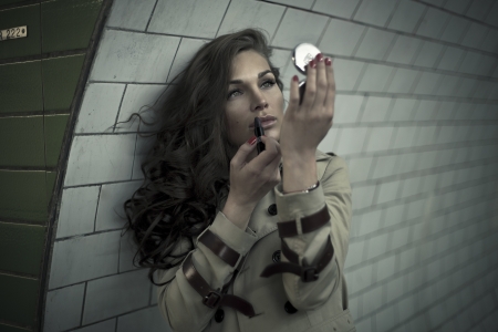Woman looking in mirror and putting lipstick in undergroundの写真素材